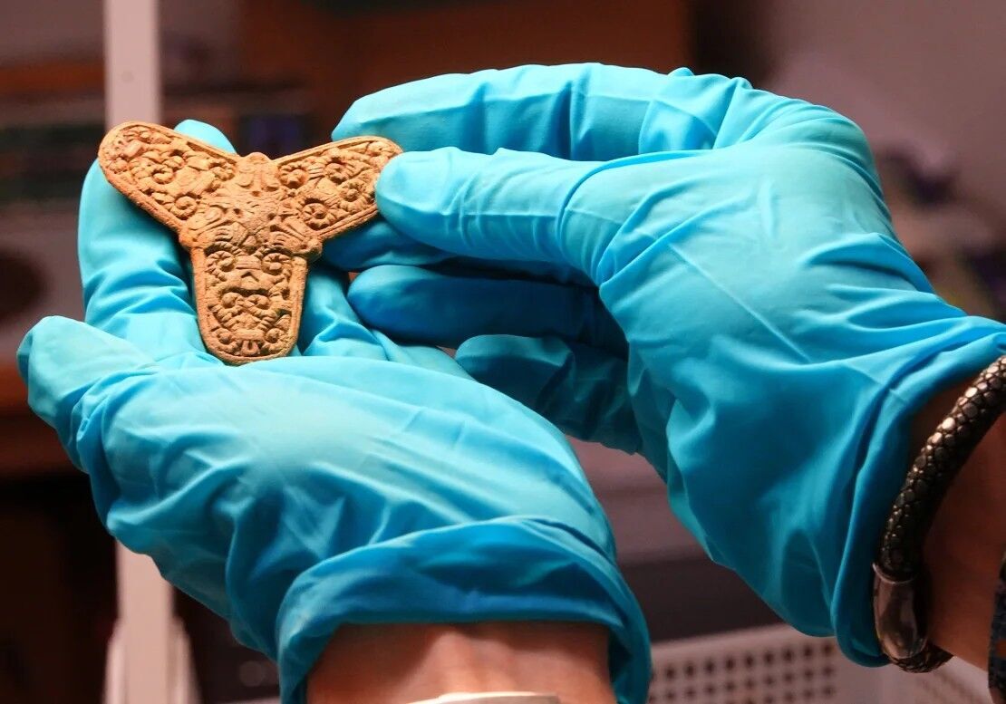 A conservator at Museum Odense displays a brooch found in a Viking-age burial site during an interview with journalists in Odense, Denmark