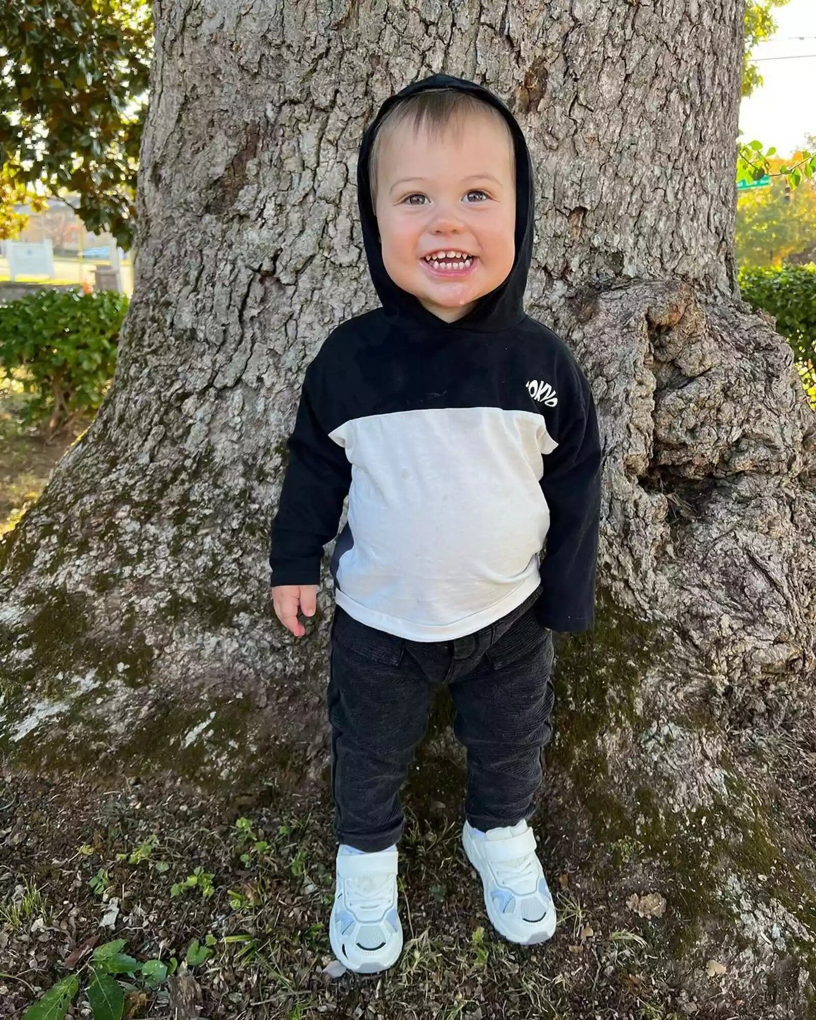 Shawn Johnson and Andrew East's son Jett James East posing next to a tree.