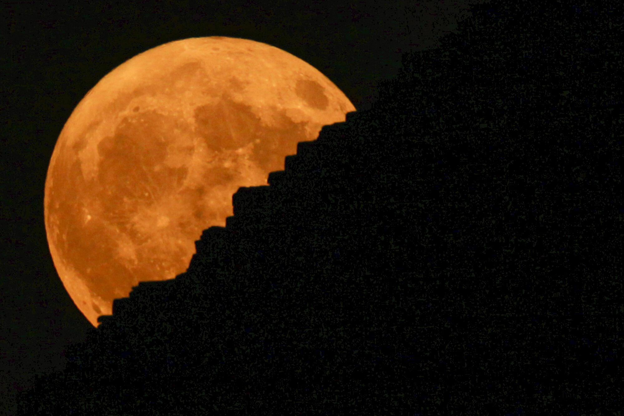 The supermoon rises behind the historical site of Giza Pyramids