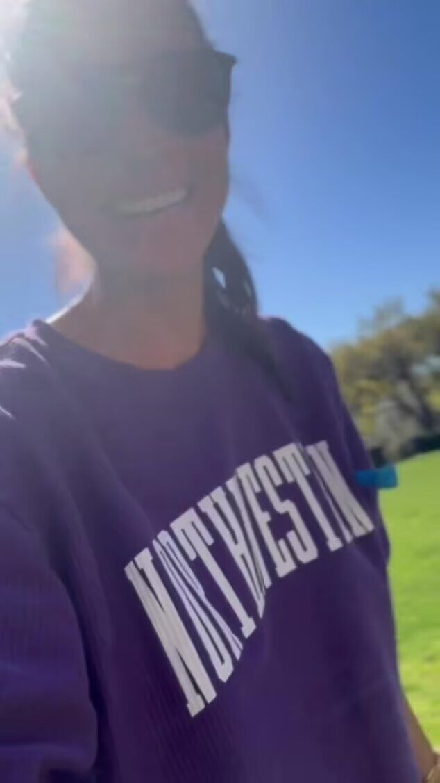 Meghan is filmed laughing and smiling in a purple Northwestern sweater that appears to match Diana's