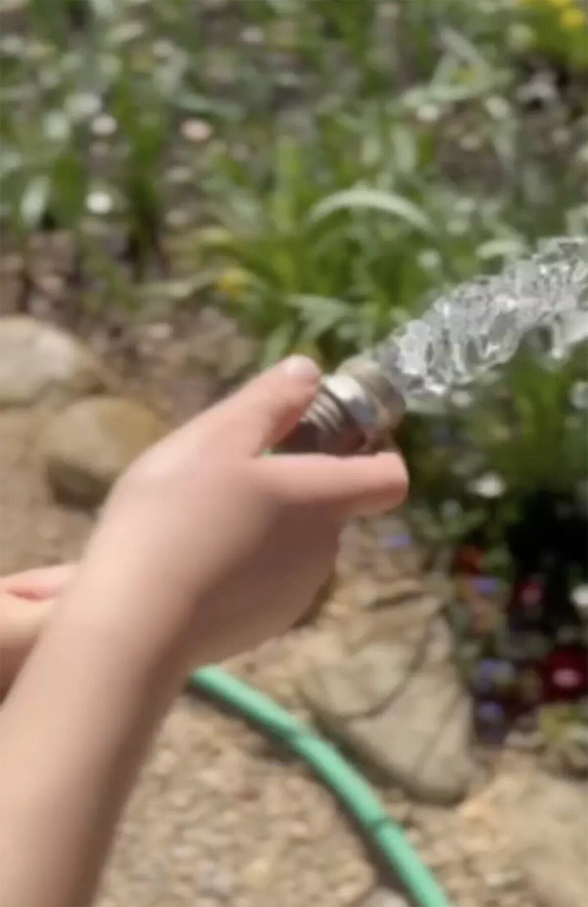 One of Meghan Markle's children helps her water the garden.