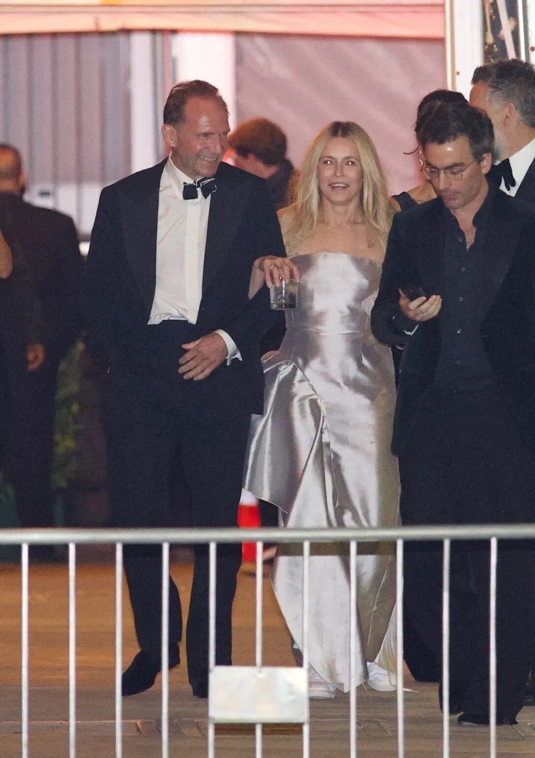 Chelsea Handler and Ralph Fiennes lock arms while leaving the 2025 Vanity Fair Oscar Party at the Wallis Annenberg Center for the Performing Arts in Beverly Hills.